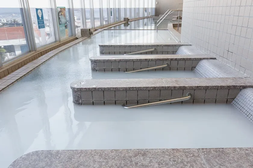 窓から街並みが望める開放的な空間に広がる、乳白色の温泉の大浴場