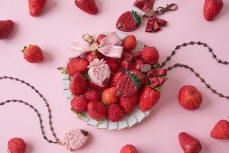 ピンク色の背景に、たくさんの新鮮なイチゴとイチゴモチーフの可愛らしいアクセサリー