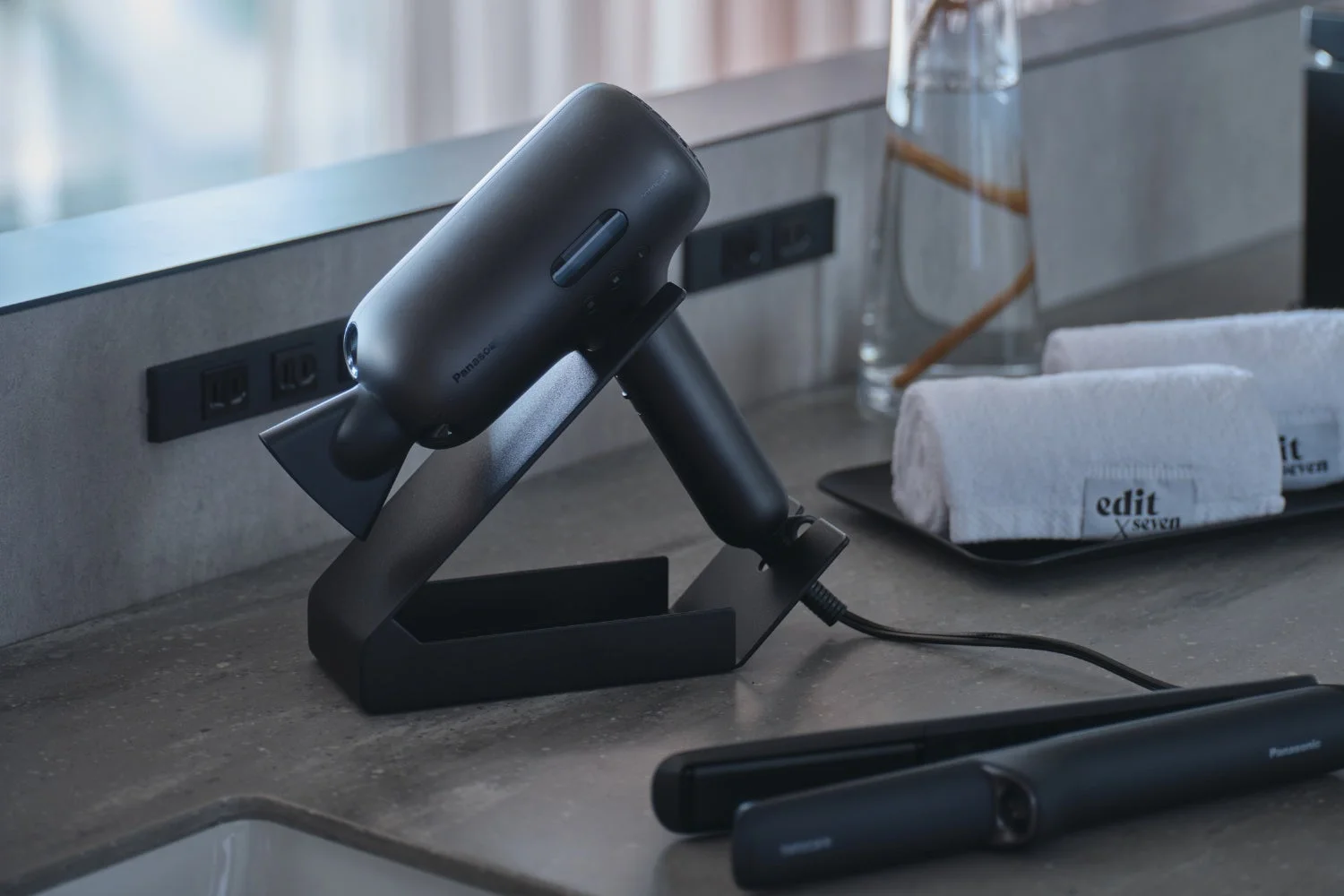 ホテルのバスルームに置かれた、黒いパナソニック製のヘアードライヤーとヘアーアイロン