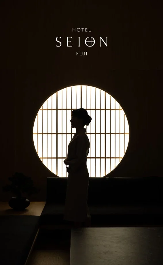 円形の障子窓を背景に、女性のシルエットが浮かび上がる神秘的な空間。和の趣を感じさせるホテルの一室で、静かで優雅な雰囲気を醸し出しています。