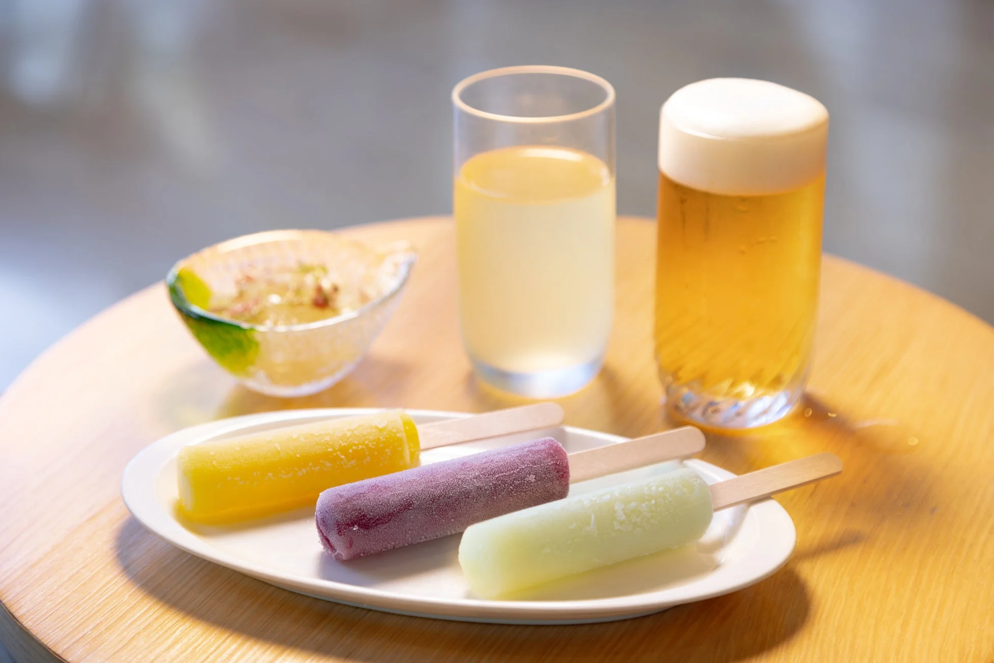 カラフルなアイスキャンディー3本が盛られた皿と飲み物