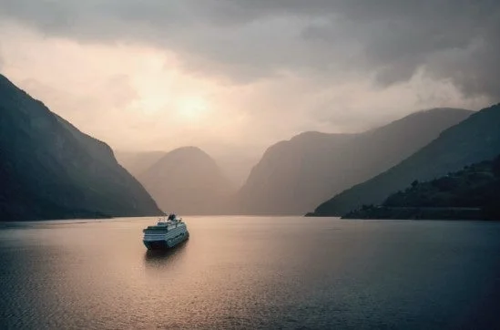 夕暮れのフィヨルドを航行するクルーズ船