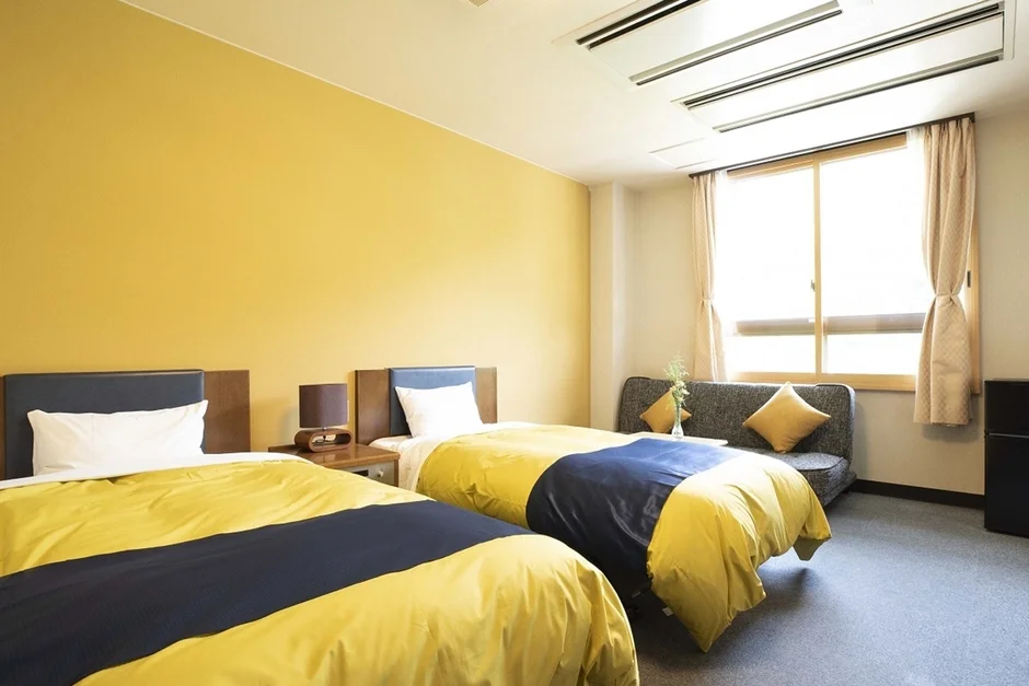 黄色い壁が印象的な、明るくモダンなホテルの一室