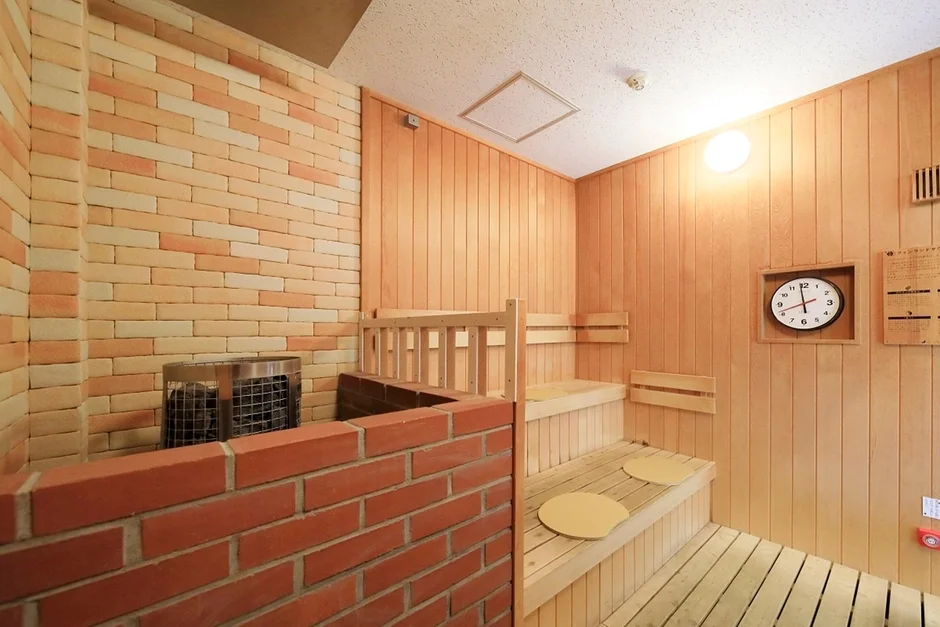 レンガの壁と木製のベンチが特徴の清潔感のあるサウナルーム