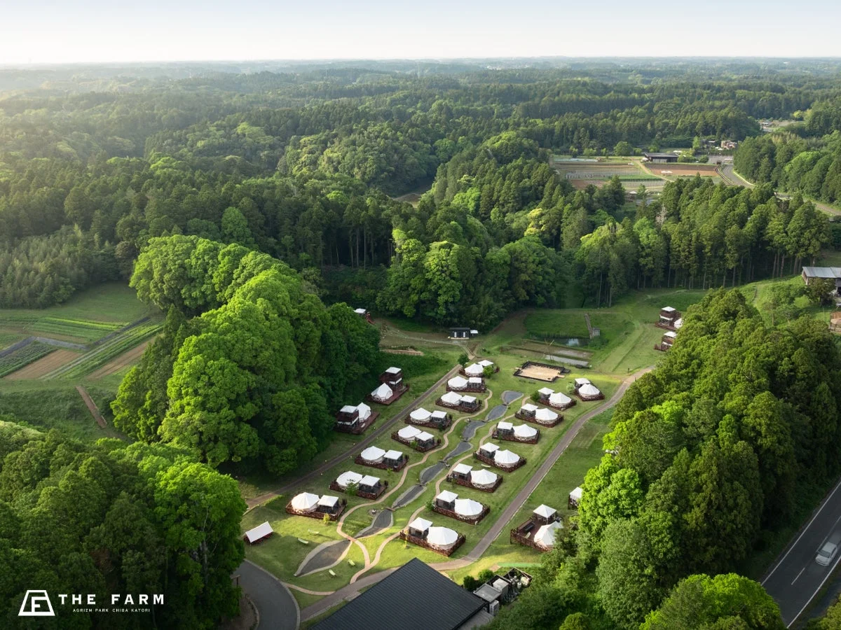 緑豊かな森林に囲まれたグランピング施設の空撮写真