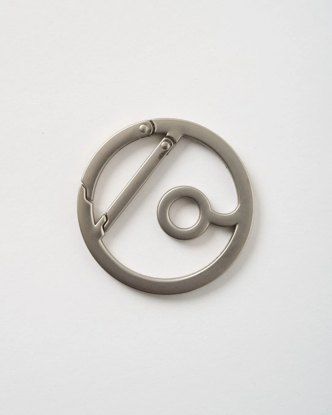 白い背景に置かれた、銀色の丸い金属製カラビナのクローズアップ