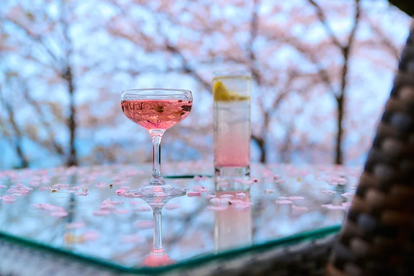桜の花びらが散りばめられたテーブルにピンク色のカクテル